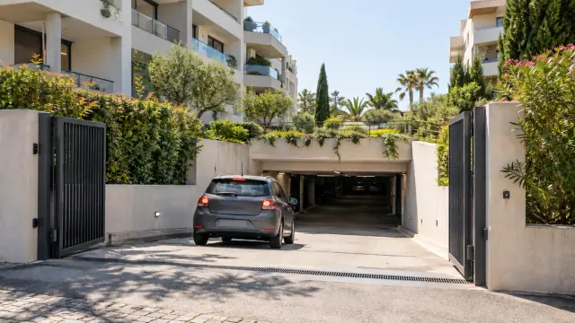 Entrée ouverte d’un parking souterrain dans une résidence entourée de végétation méditerranéenne