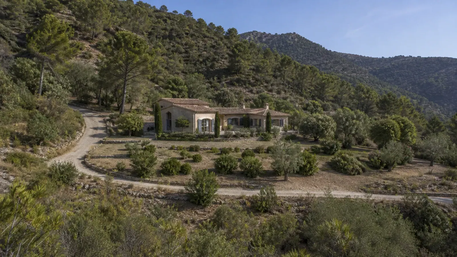 Villa en pierre entourée de végétation méditerranéenne entretenue sur une colline boisée