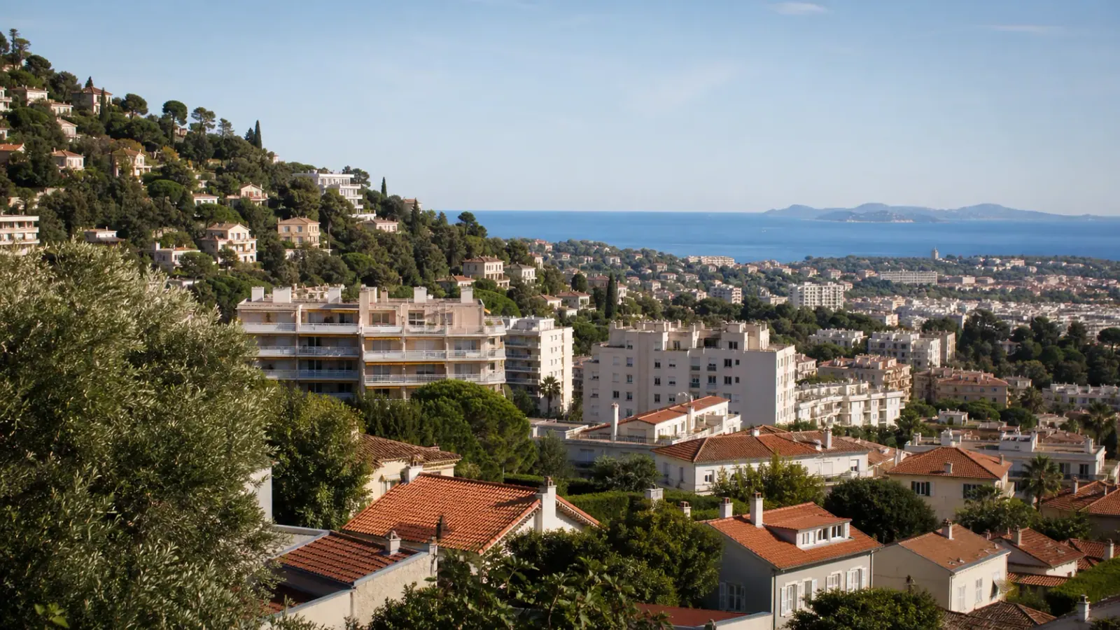 Quartier résidentiel vallonné des Alpes-Maritimes avec immeubles, villas et mer au loin